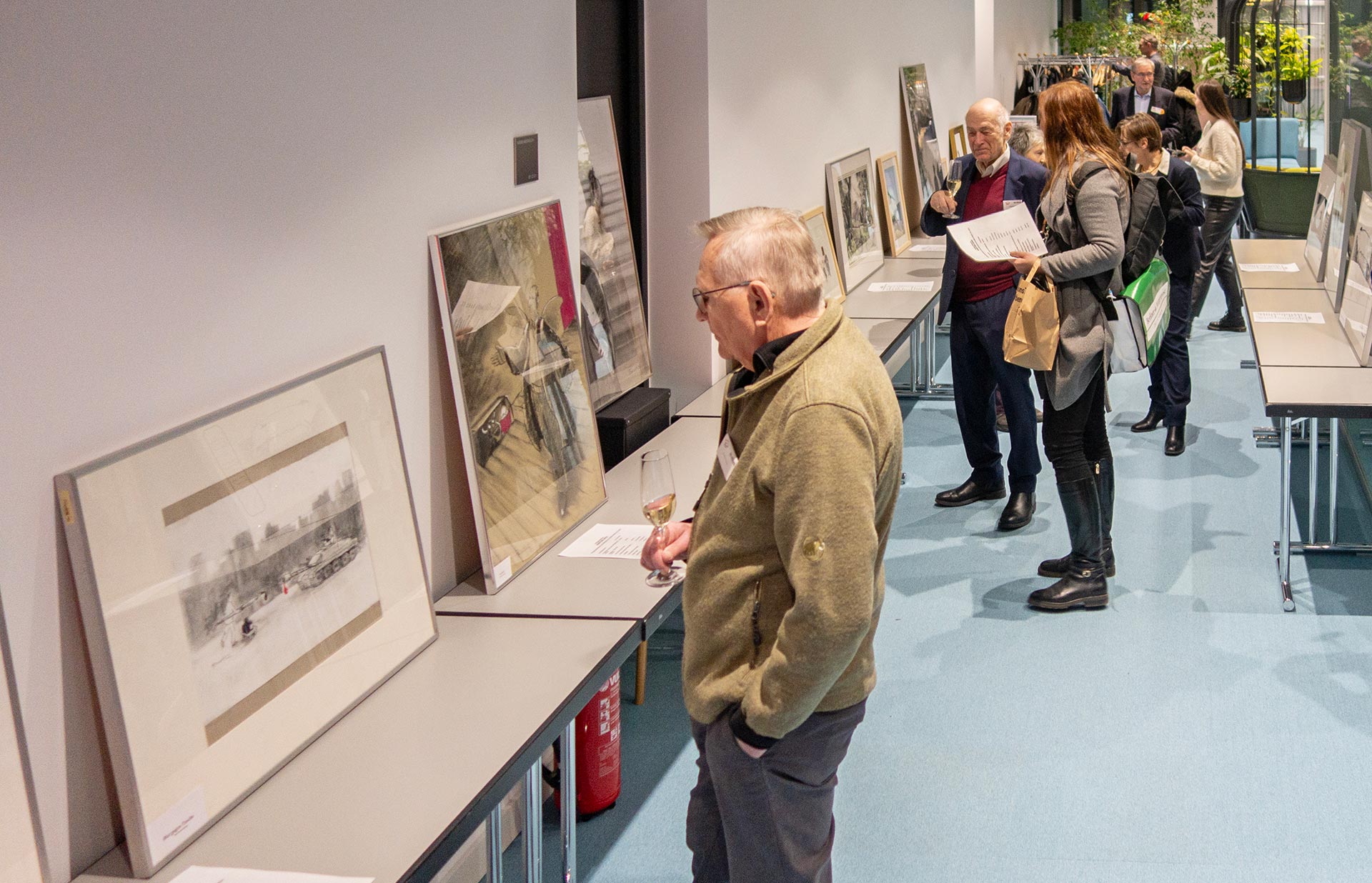 Gäste betrachten aufgestellte Karikaturen von Philipp Heinisch